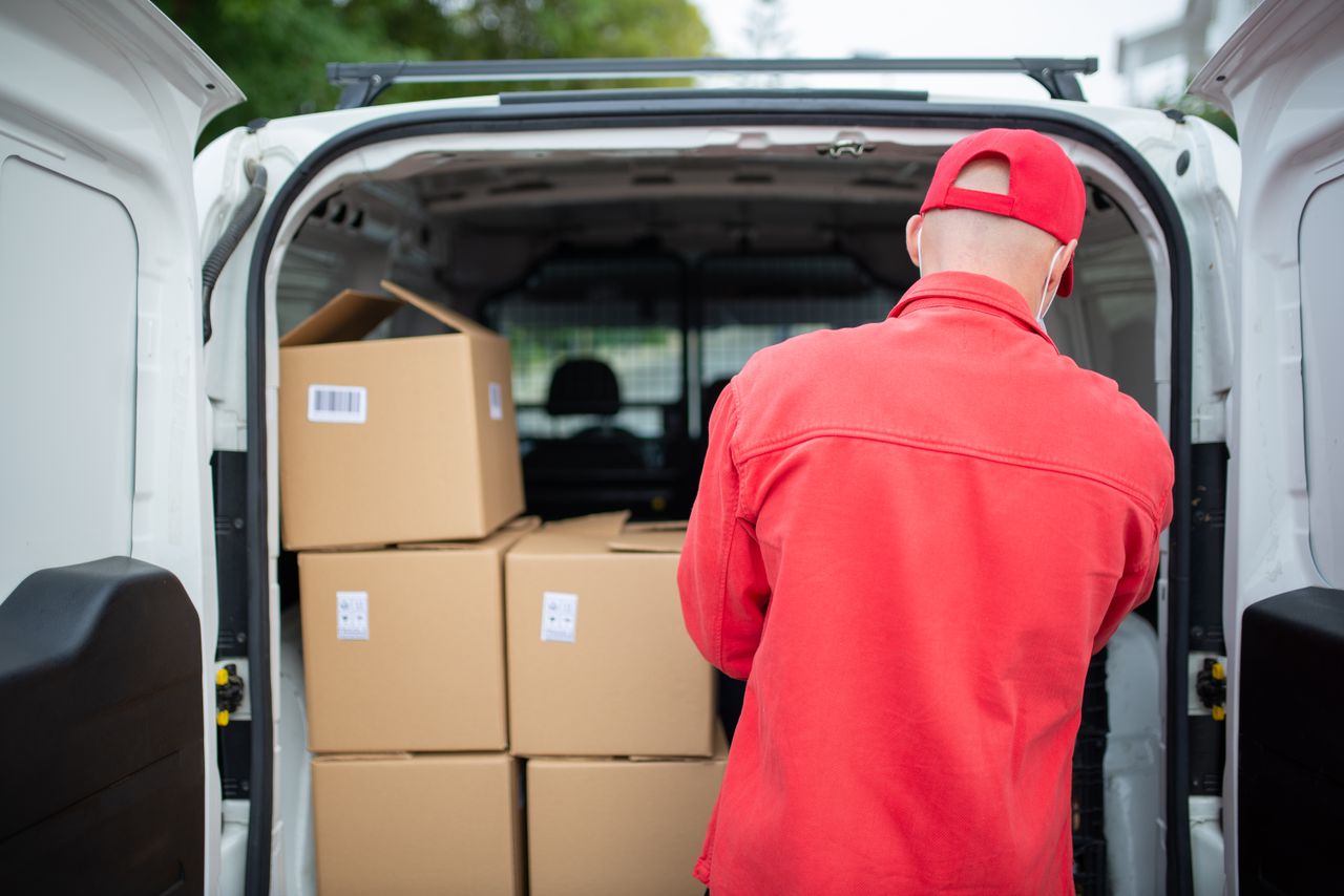Mastering the First Impression: Your intriguing post title goes here Courier in red loading cardboard boxes into a delivery van outdoors in Portugal.